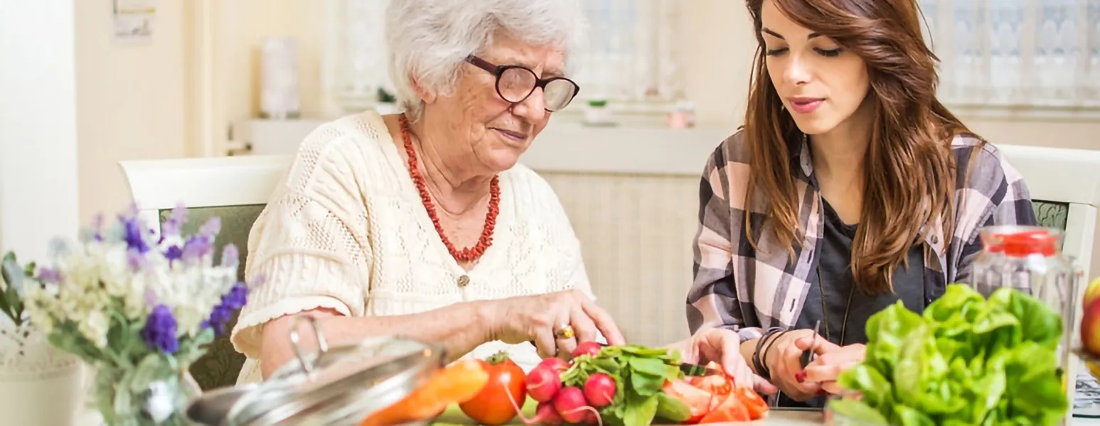 Caregiver preparing a meal with a senior woman